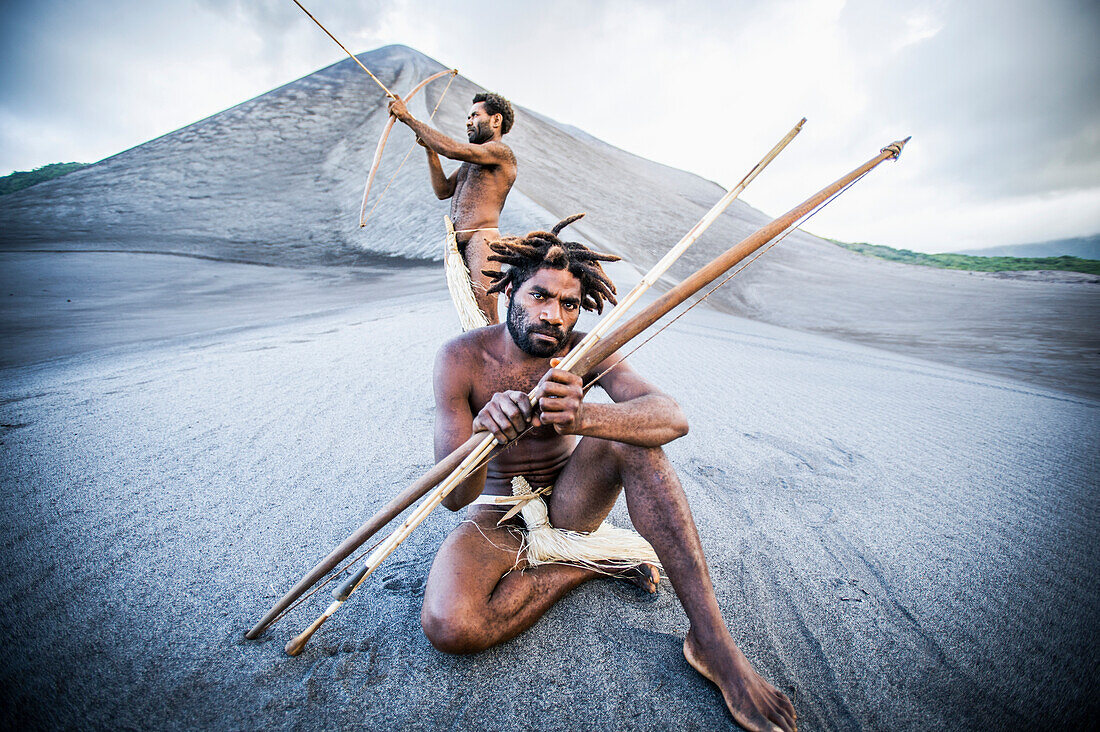 Two ni-Vanuatu men with bows and arrows at the base of Yasur Volcano, Tanna Island, Vanuatu