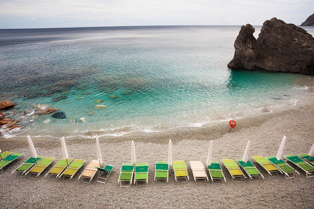 Beach chairs along the water's edge and a view of the horizon, Monterosso Al Mare, Liguria, Italy