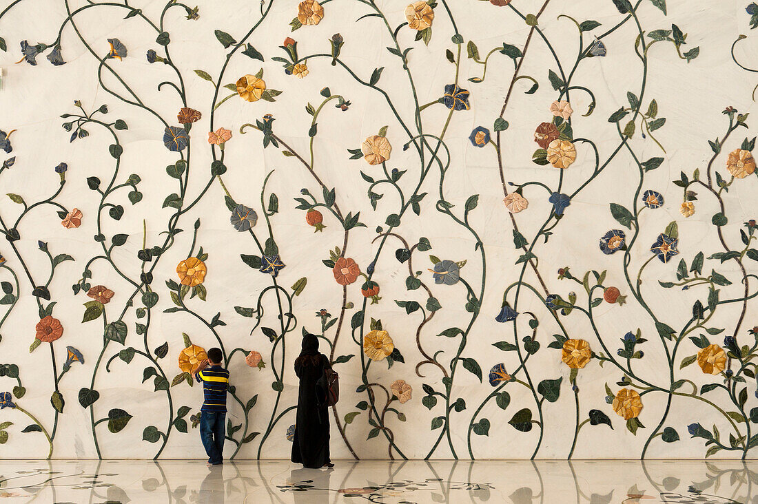 Mother and son in front of decorated wall in the Sheikh Zayed Grand Mosque, Abu Dhabi, United Arab Emirates
