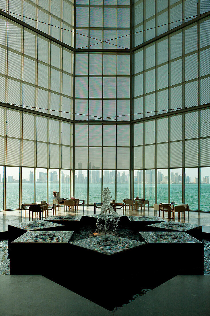 Man relaxing in front of large window in the Museum of Islamic Art, Doha, Qatar