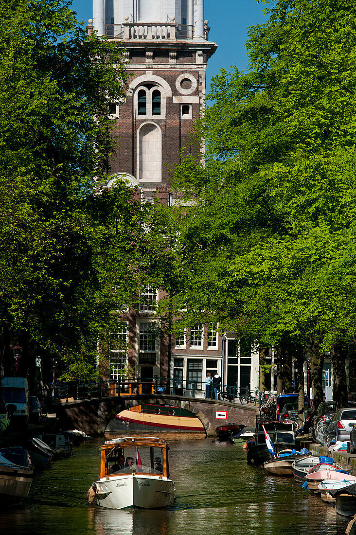 Small boat going along canal with the Zuiderkerk church at the end, Amsterdam, Holland
