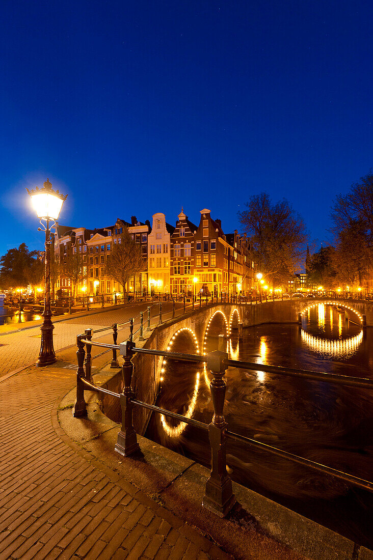 Bridges over canals at dusk with streak of lights from boat, Amsterdam, Holland