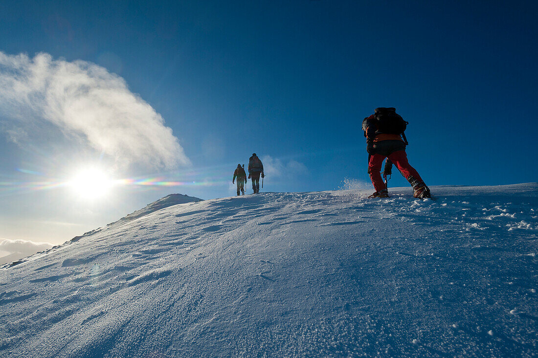 Walkers climbing the snowy slopes of Sgorr Dhearg near Glen Coe, Highlands, Scotland
