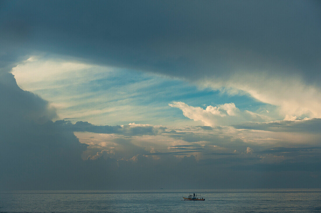 Fishing boat with hole in stormy clouds behind, near Unawatuna, Sri Lanka