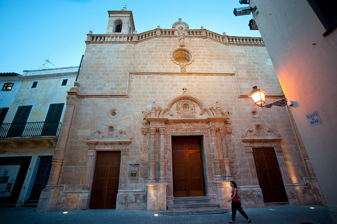 Girl Passing In Front Of Esglesia Del Roser, A Church In Ciutadella, Menorca, Balearic Islands, Spain