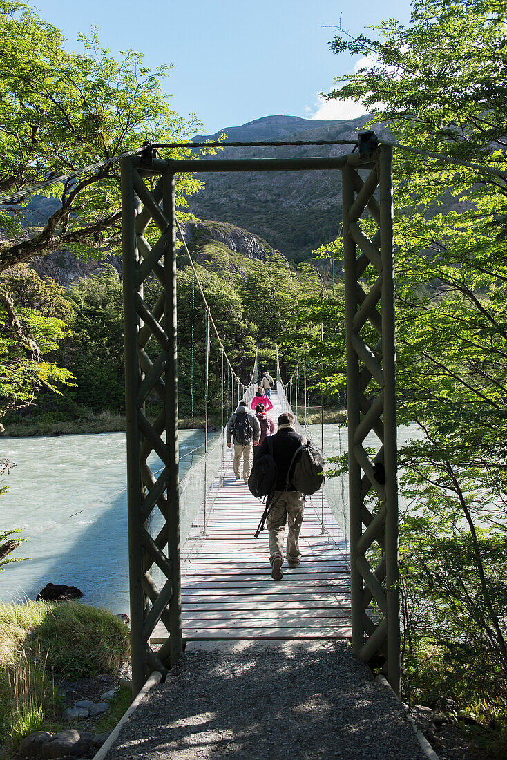 'Tourists walking on a bridge over a river, Torres del Paine National Park; Torres del Paine, Magallanes and Antartica Chilena Region, Chile'