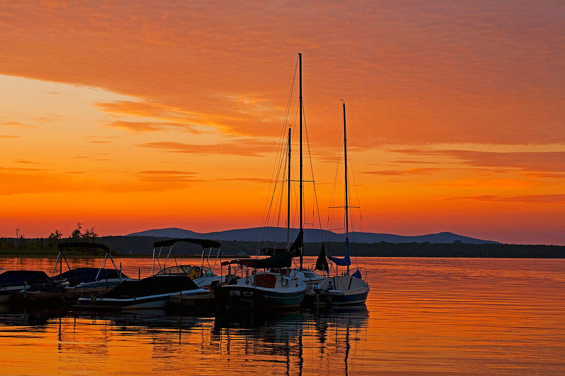 'Red sunset over a lake with boats; Knowlton, Quebec, Canada'