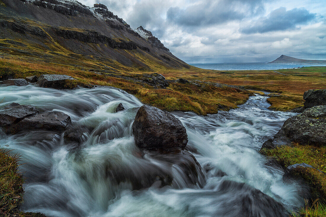 'A large stream runs down a hillside creating a waterfall along the Strandir Coast in the West Fjords of Iceland; Iceland'