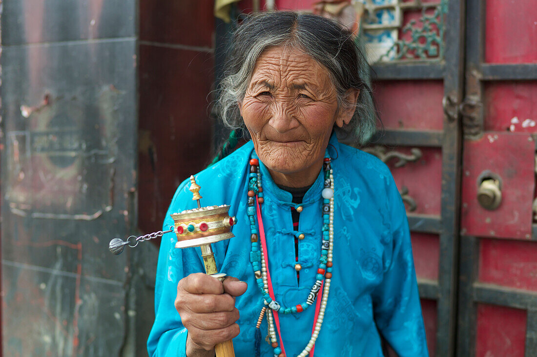 'Elderly woman spins prayer wheel; Manigange, Sichuan, China'