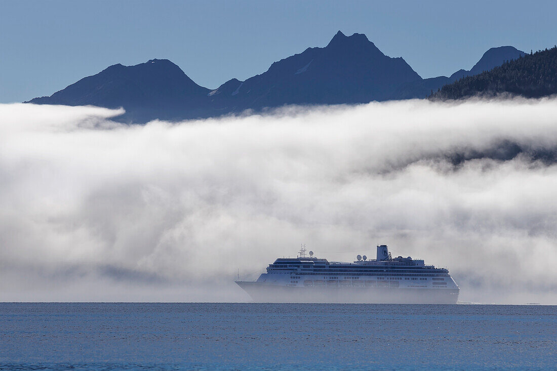 A cruise ship, the Zaandam Holland America, travels along the edge of a fog bank in Taku Inlet on its way to Juneau, Southeast Alaska