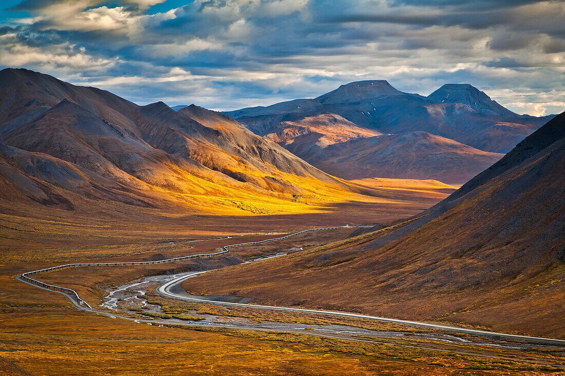 Sunset lighting Brooks Range at Chandalar Shelf, viewed from Atigun Pass between Gates of the Arctic National Park & preserve and Arctic National Wildlife Refuge with Dalton Hwy and pipeline cutting through the valley. Arctic Alaska, Autumn.