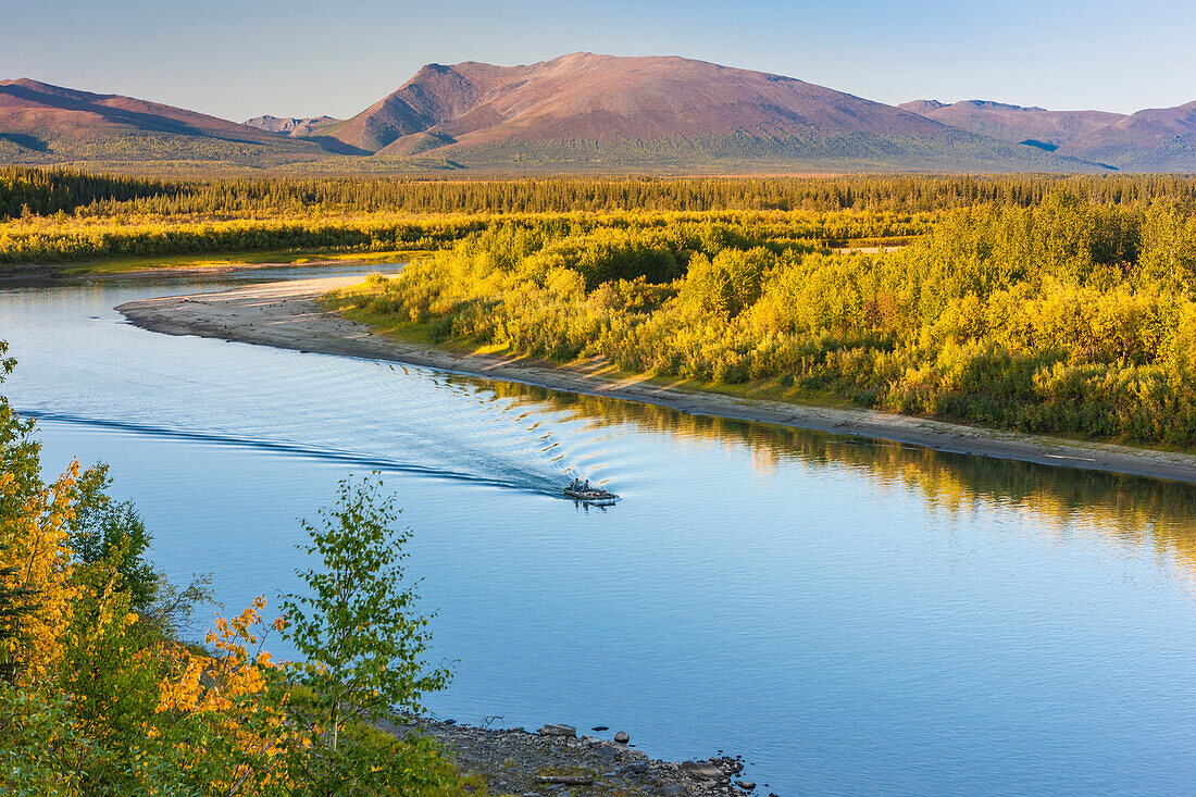 a small boat motors down the Kobuk river on a calm sunny day, Arctic Alaska, summer