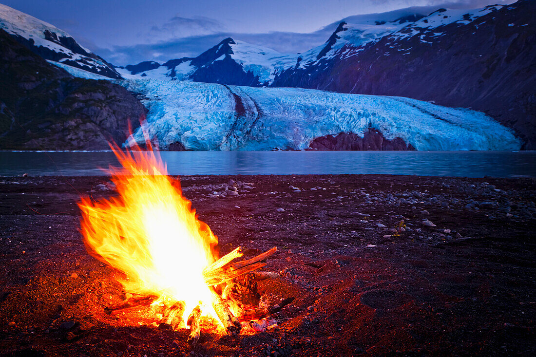 Close up of campfire in front of Portage Glacier at dusk, Chugach National Forest, Kenai Peninsula, Southcentral Alaska, Summer.
