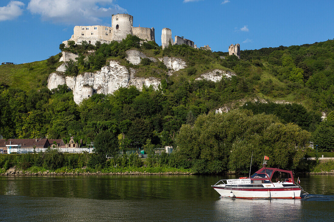 small private cruise boat liberte seine on the river in front of the medieval fortress of chateau gaillard built by the english king richard the lionhearted in 1198, les andelys, eure (27), normandy, france