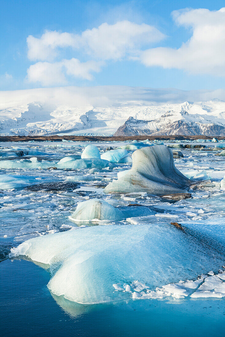 Mountains behind the icebergs locked in the frozen water of Jokulsarlon Iceberg Lagoon, Jokulsarlon, South East Iceland, Iceland, Polar Regions