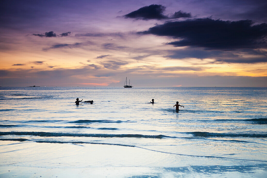 Swimming in the ocean at sunset at Cenang beach, Langkawi, Malaysia