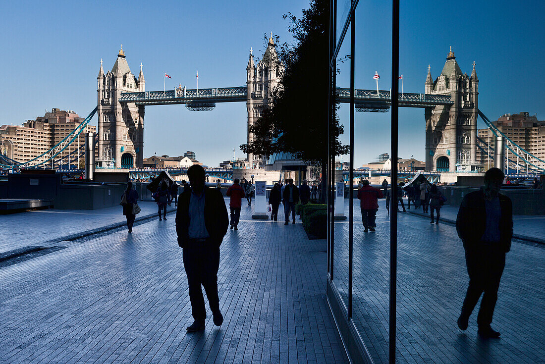 Pedestrians on a walkway with London's tower bridge in the background, London, England