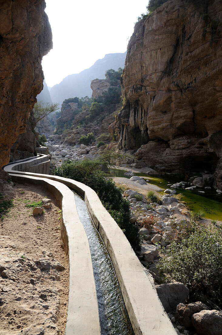Sultanate of Oman Wadi TIWI an irrigation canal above a canyon in the middle of the mountains with an emerald green water river
