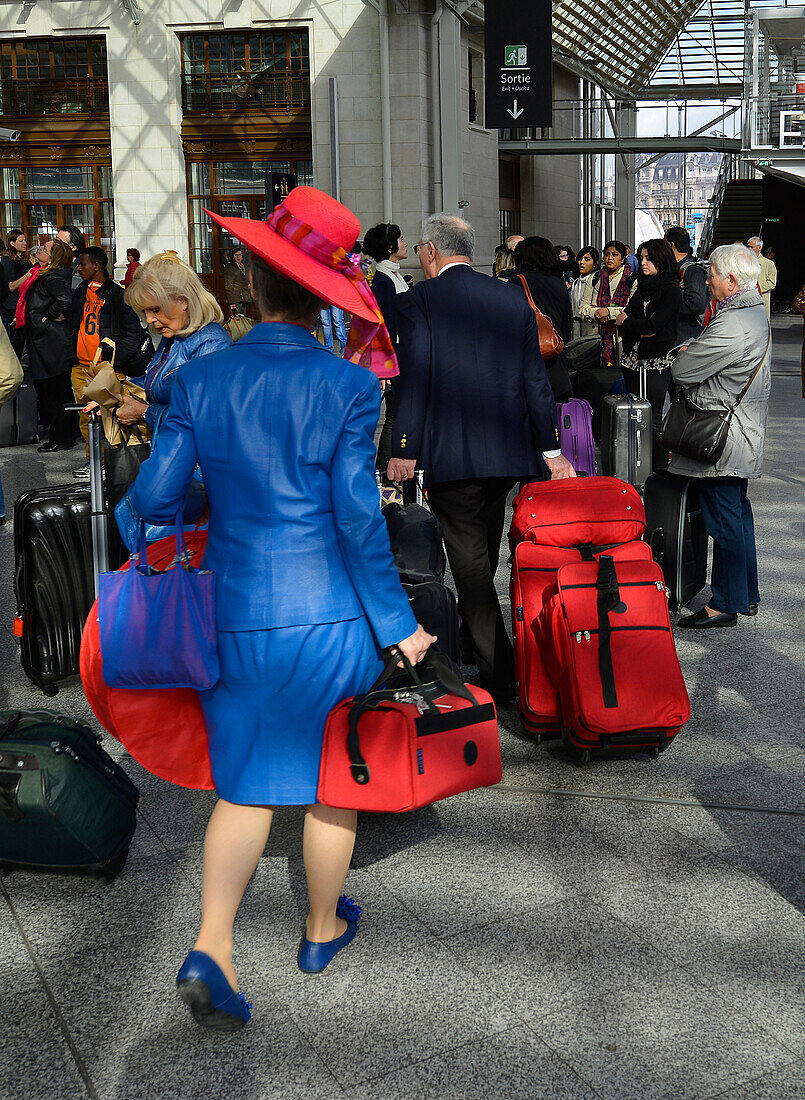 Europe, France, Paris, in the hall of the Gare de Lyon, a woman in blue large red hat amid travelers, Bags of the same color