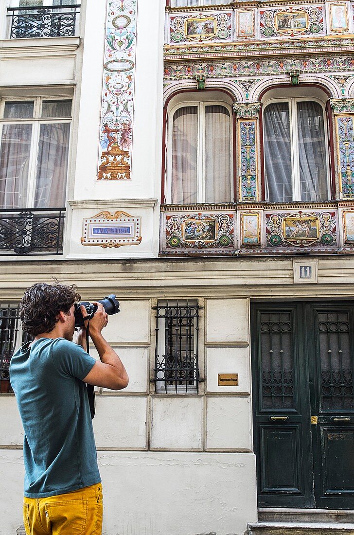 Young man taking photos of a Parisian building