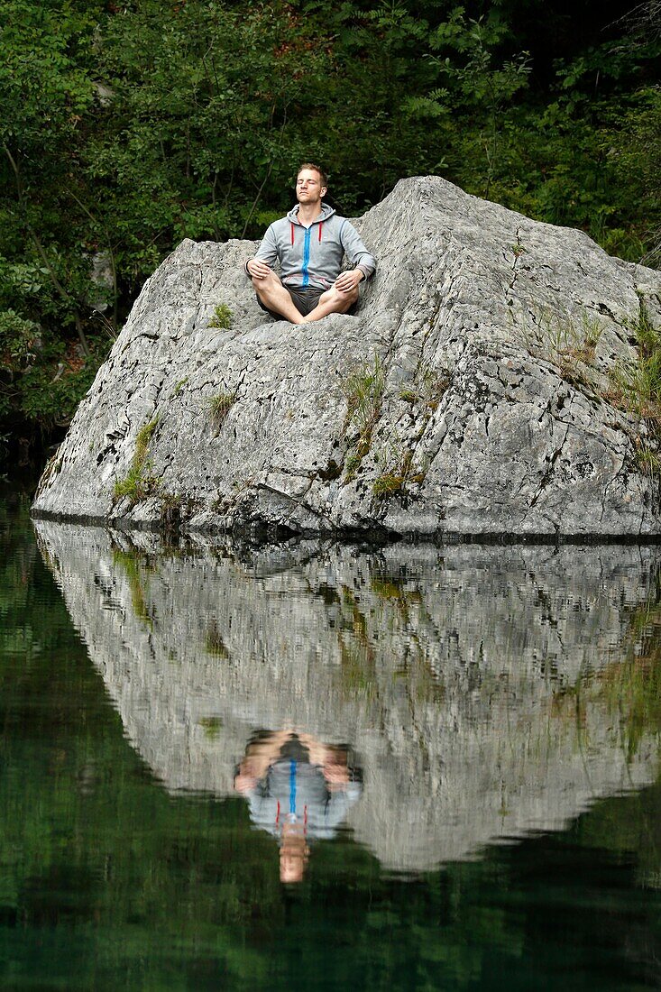 Man praying in front of a lake