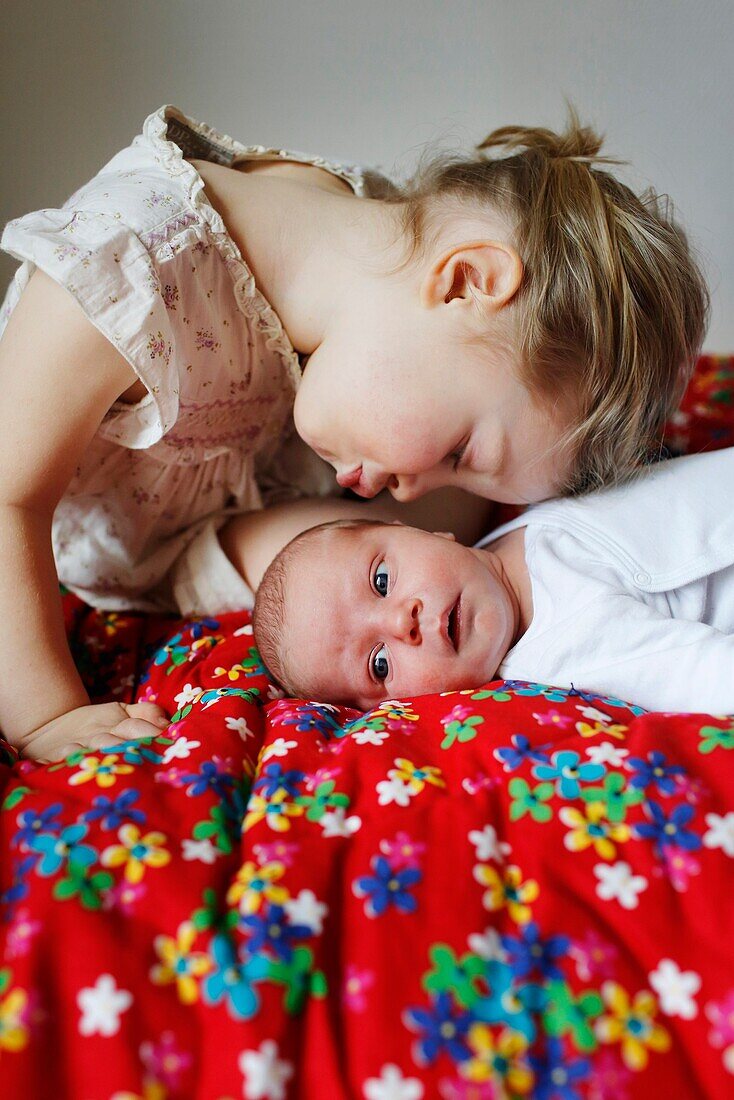 A 3 years old girl kissing her newborn brother