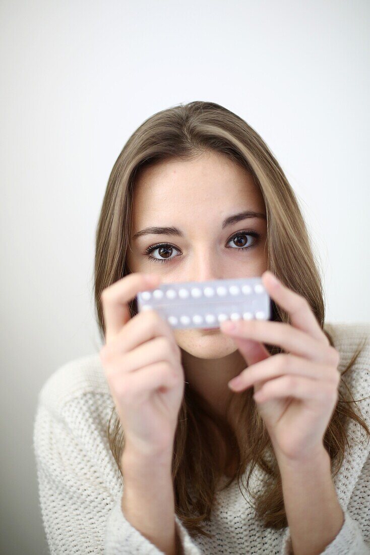 A teenage girl posing with a plate of contraceptive pills