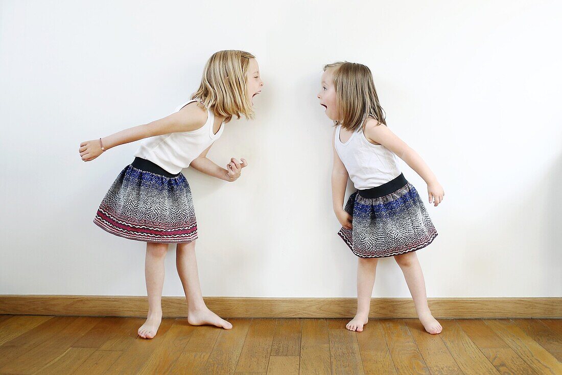 2 sisters, 3 and 5 years old, dressed in the same way squabble