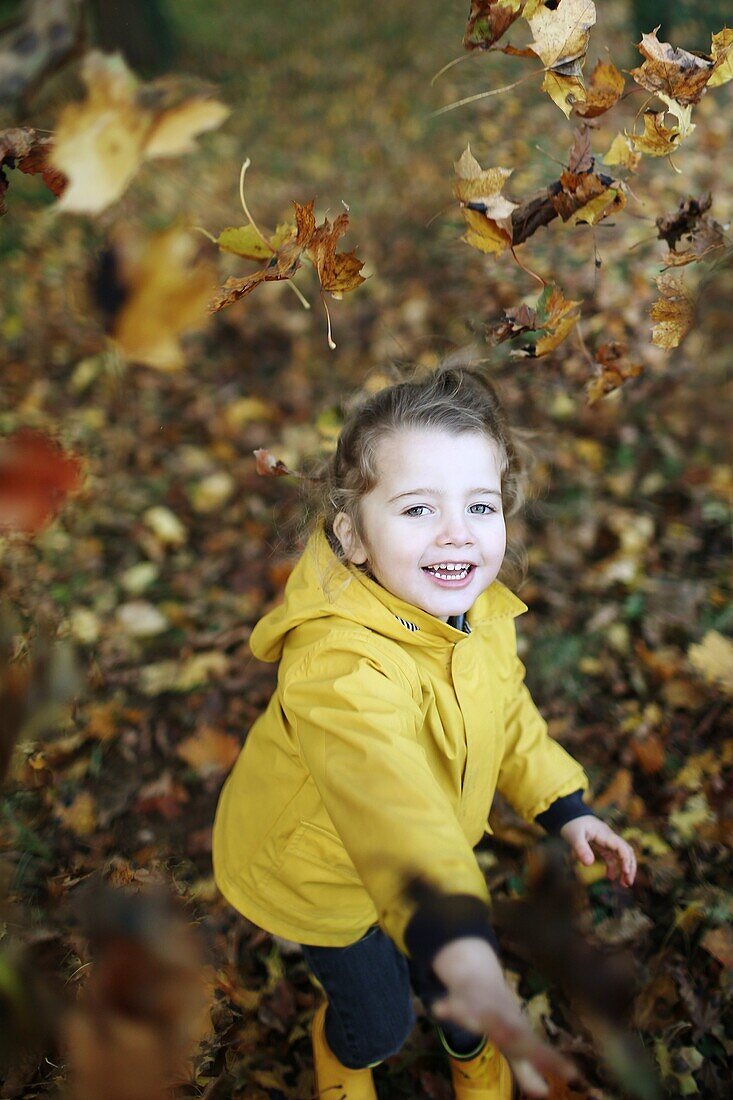 A little girl playing with dead leaves