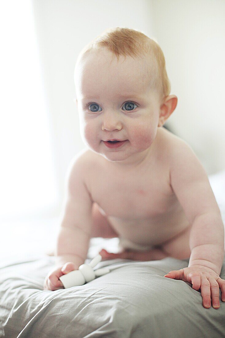 Portrait of a 9 months hold baby girl on a bed