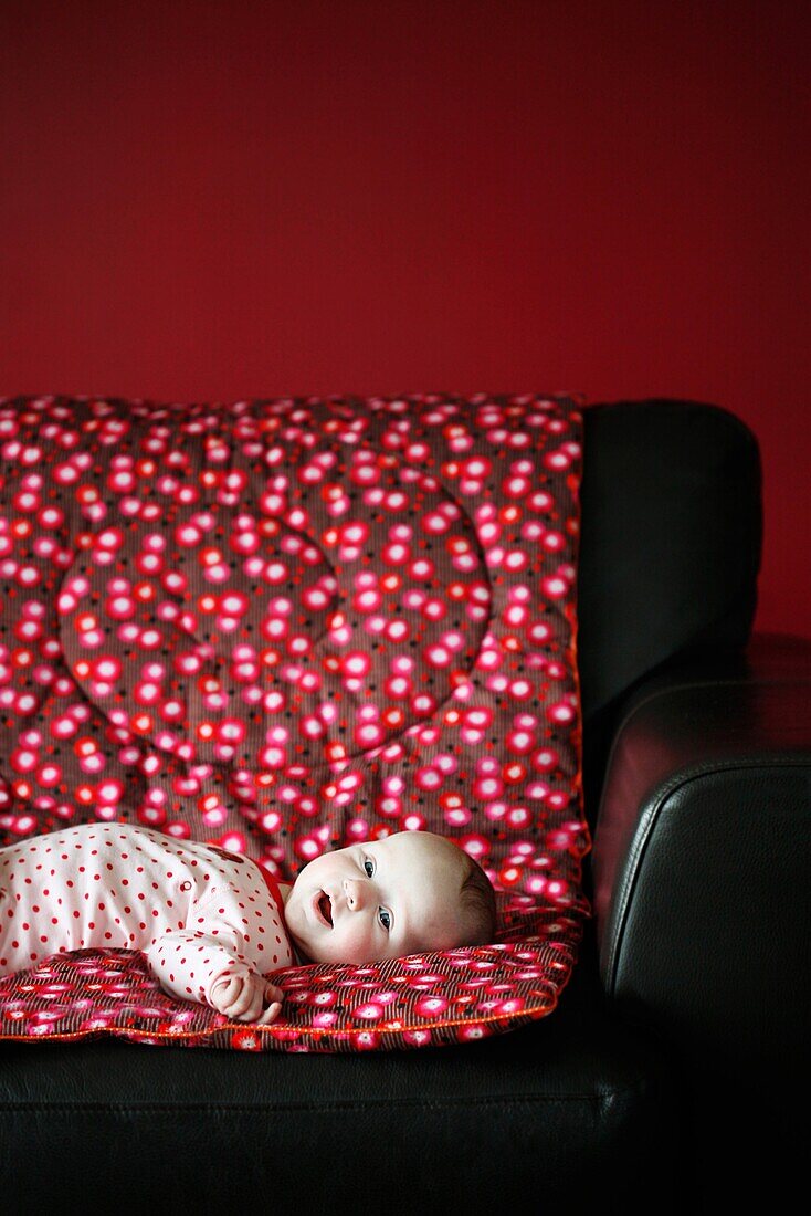 Portrait of a 4 months baby girl liying on a sofa