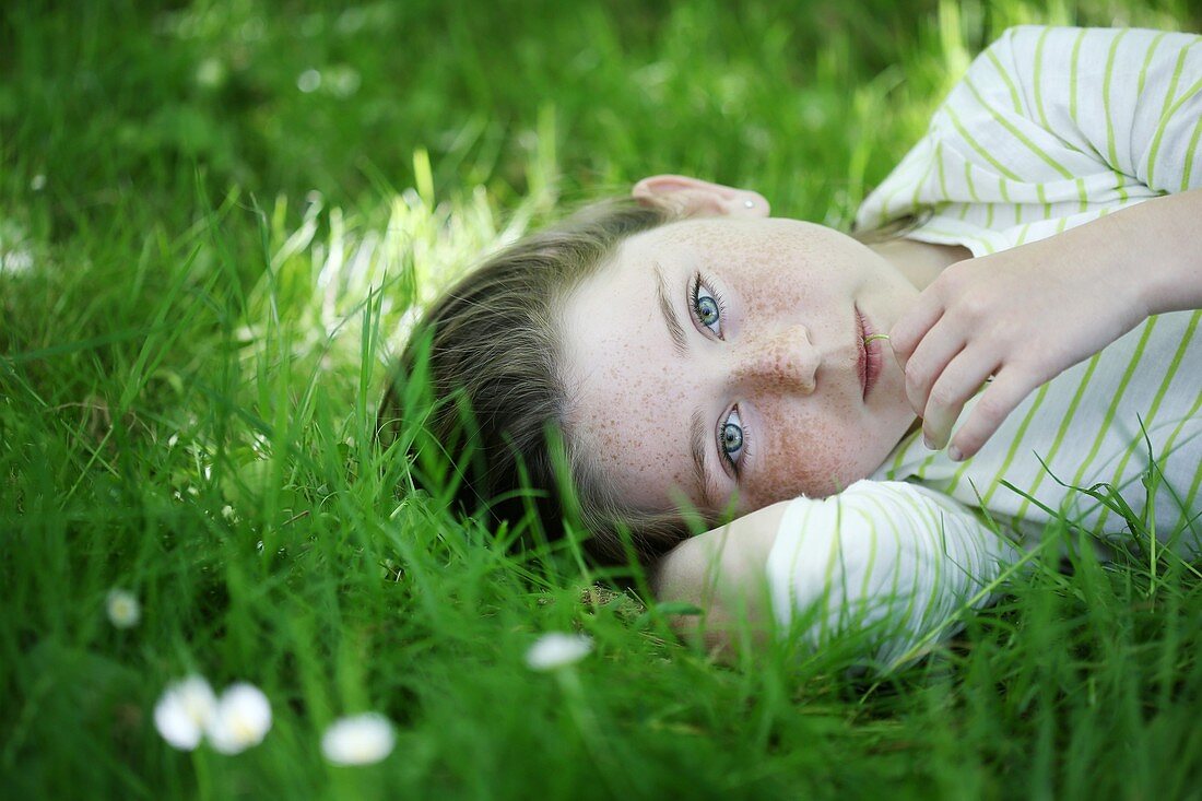 Portrait of a 9 years old girl elongated in the grass