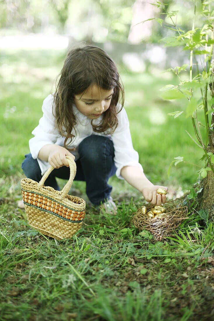 A 5 years old girl picking up Easter eggs in the countryside