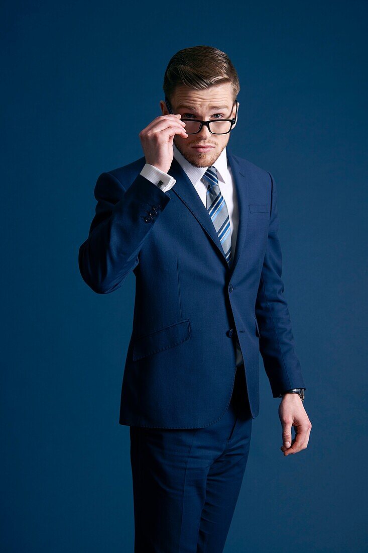 man in blue suit, glasses, tie, blue background
