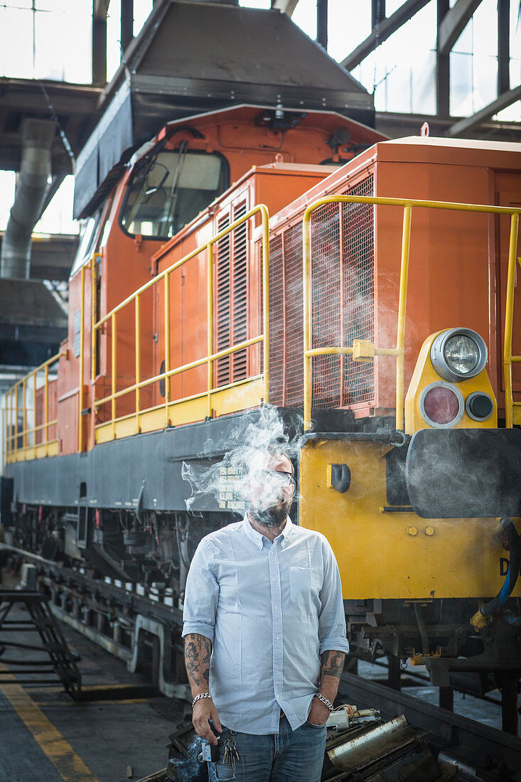 Caucasian man blowing smoke in train yard