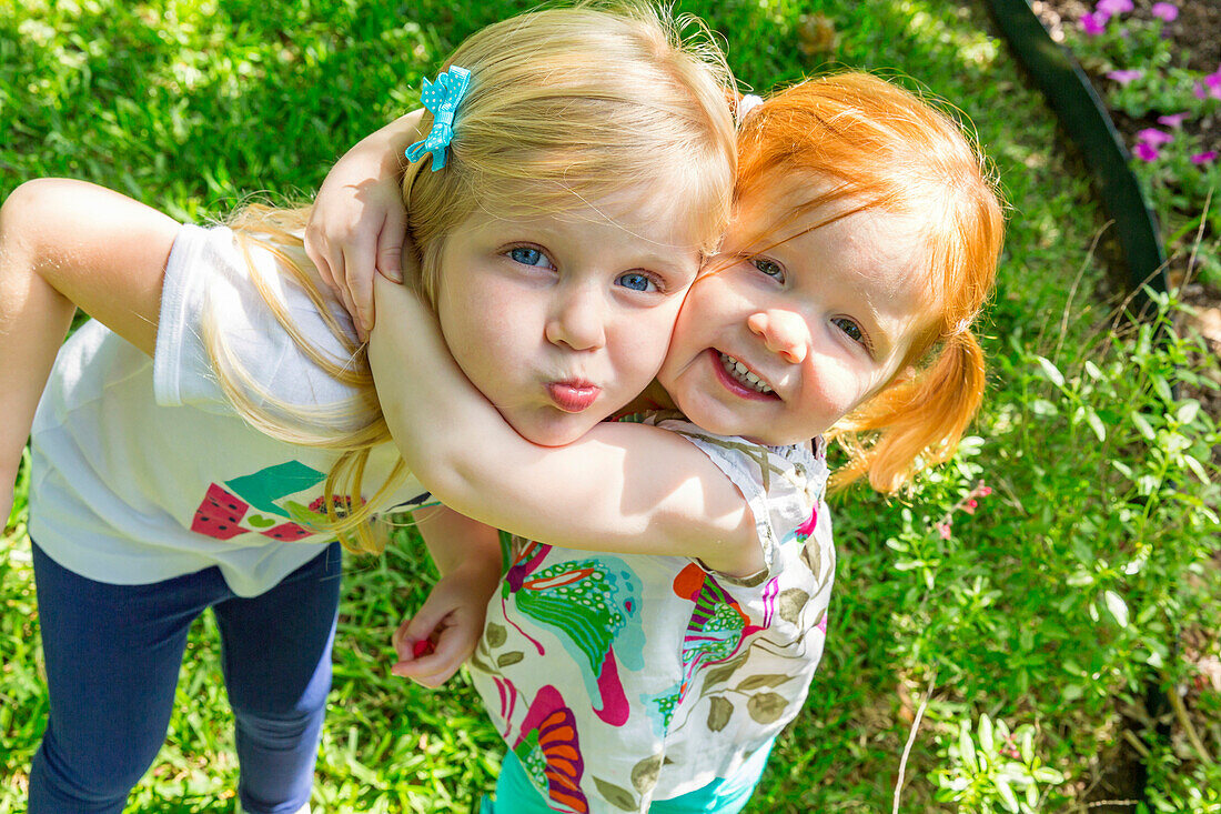 Caucasian sisters hugging in backyard