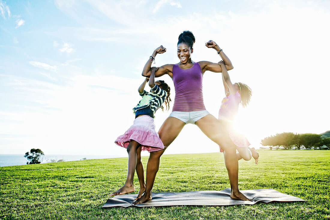 Woman lifting children with biceps in park