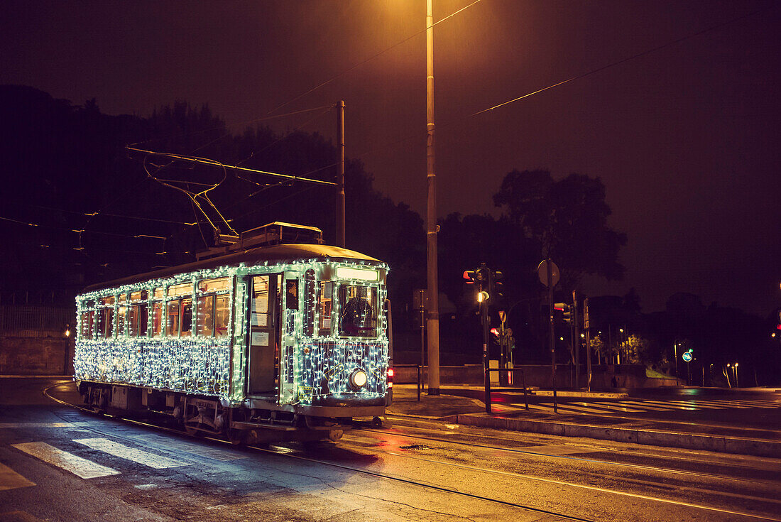 Illuminated streetcar on city street, Rome, Italy