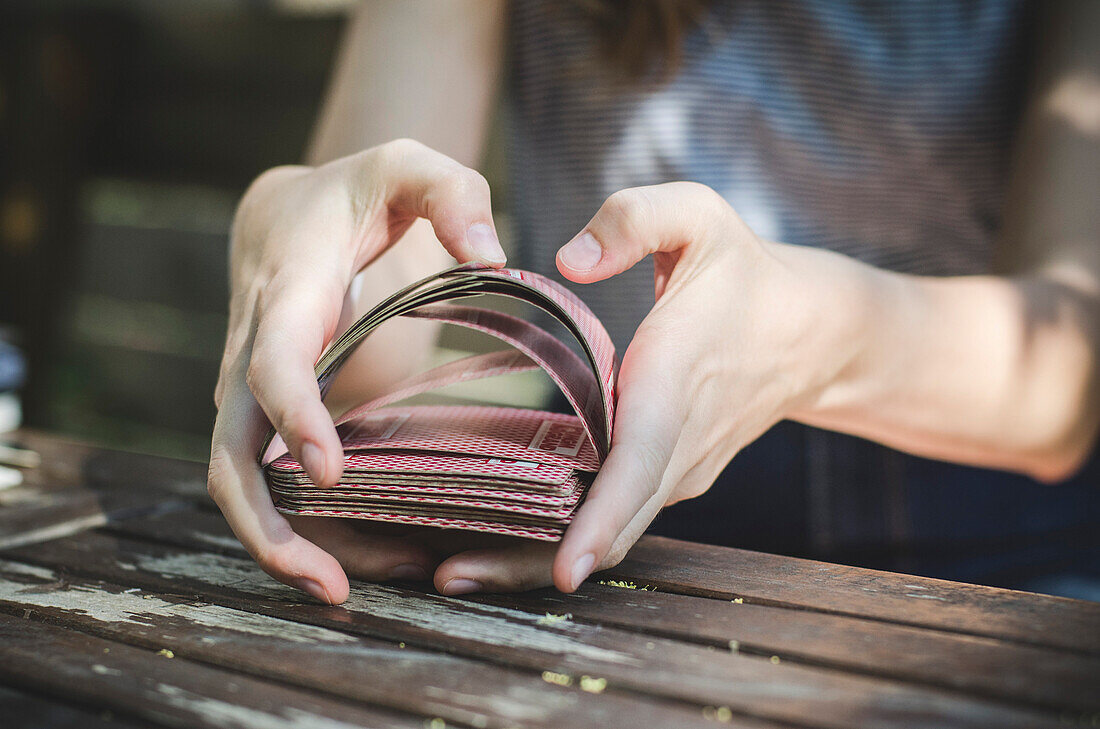 Young Woman's Hands Shuffling Playing Cards Outside
