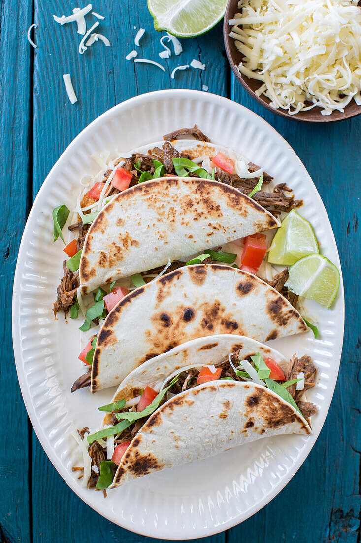 Soft Shell Tacos with Shredded Beef on White Plate, High Angle View