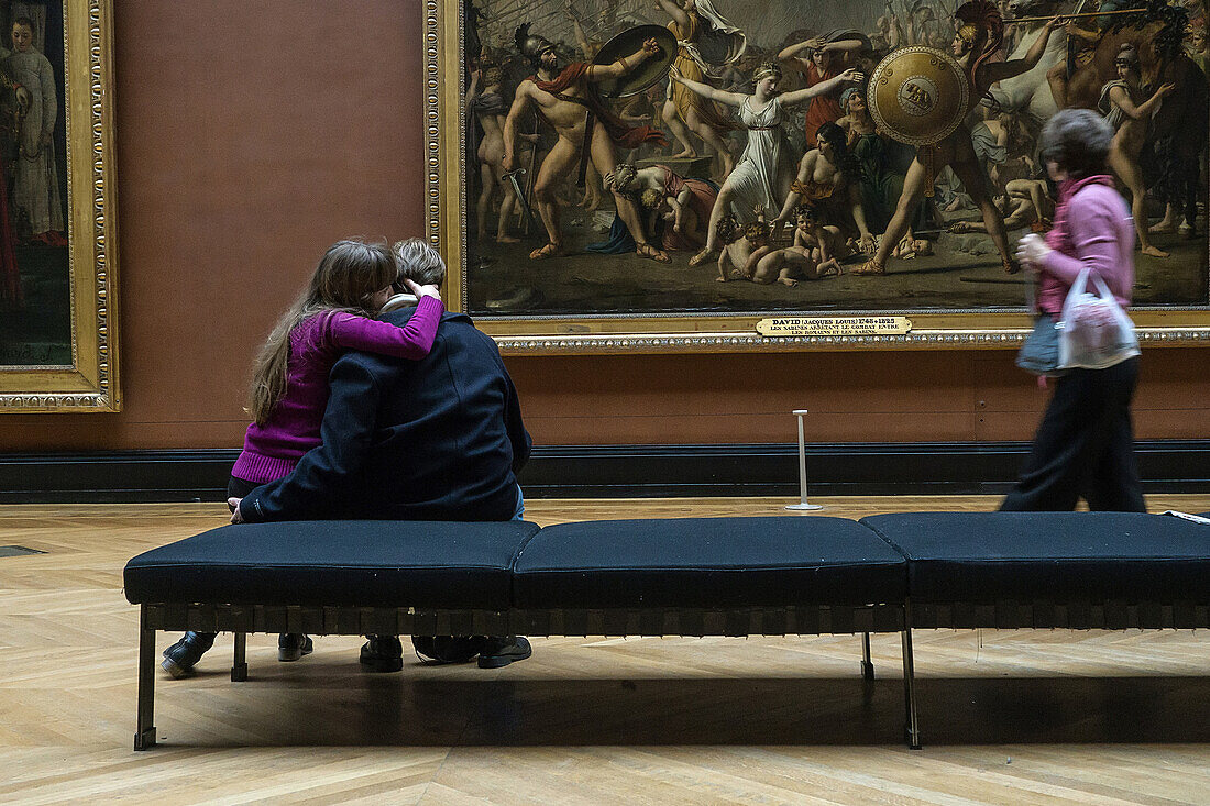couple of visitors in front of the intervention of the sabine women by jacques-louis david, hall of french paintings, museum of the louvre, paris (75), france