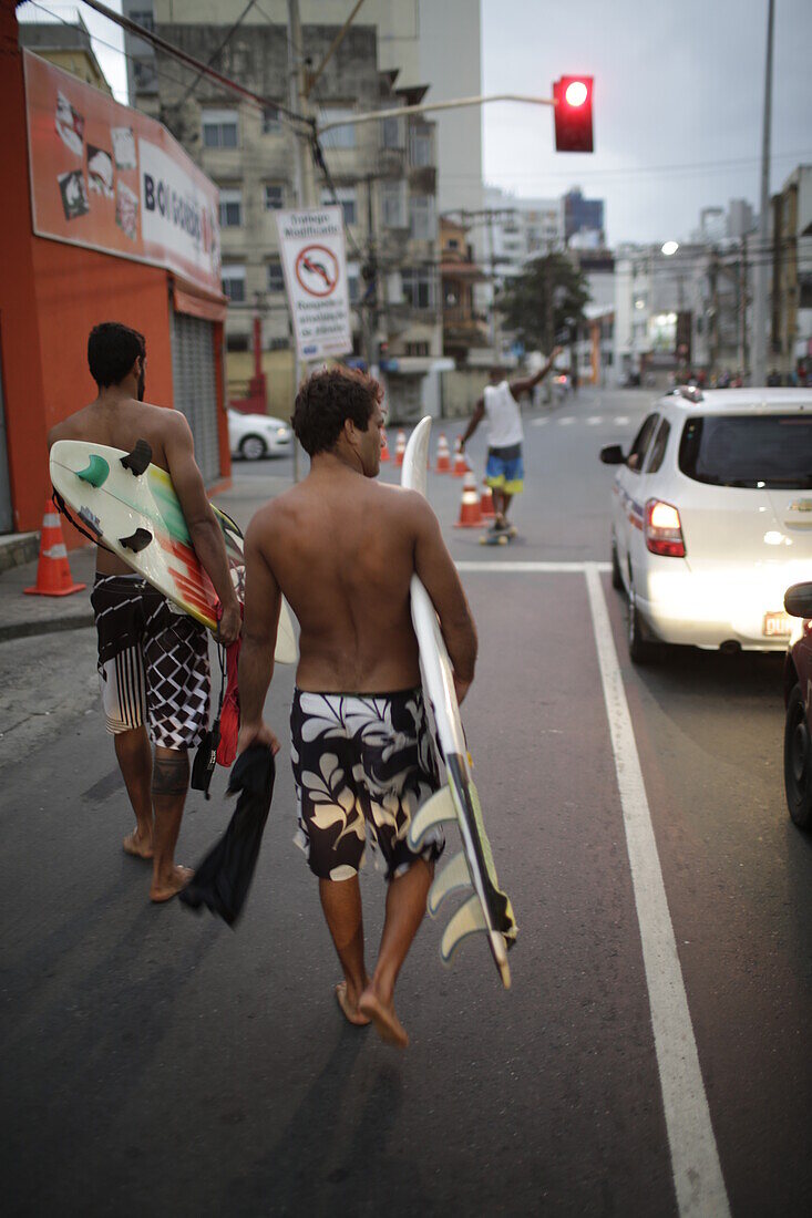 Surfers in the evening, coming from the beach on Avenida Oceanica, Barra, Salvador de Bahia, Bahia, Brazil