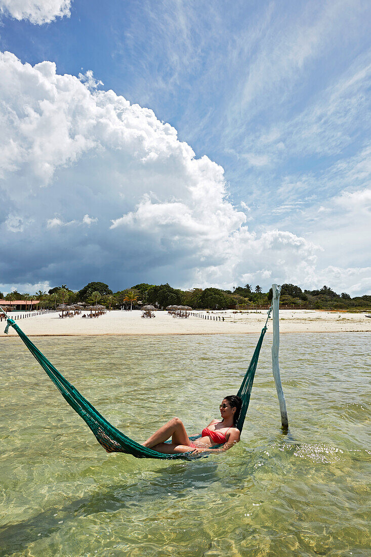 Lagoa do Paraiso, visitor bathing in a hammock at the resort Chez Loran, lagoon near Jericoacoara, Ceara, Brazil