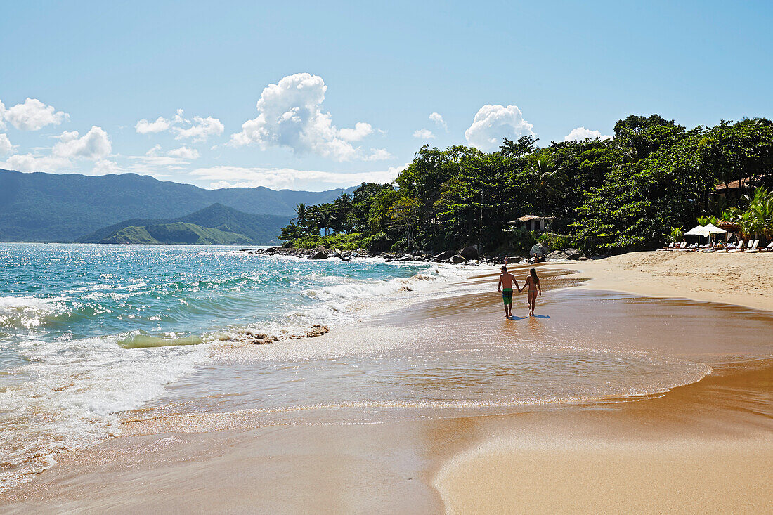 Couple walking hand in hand on the beach, Praia do Curral, western side of the island Ilhabela, Costa Verde, Sao Paulo, Brazil