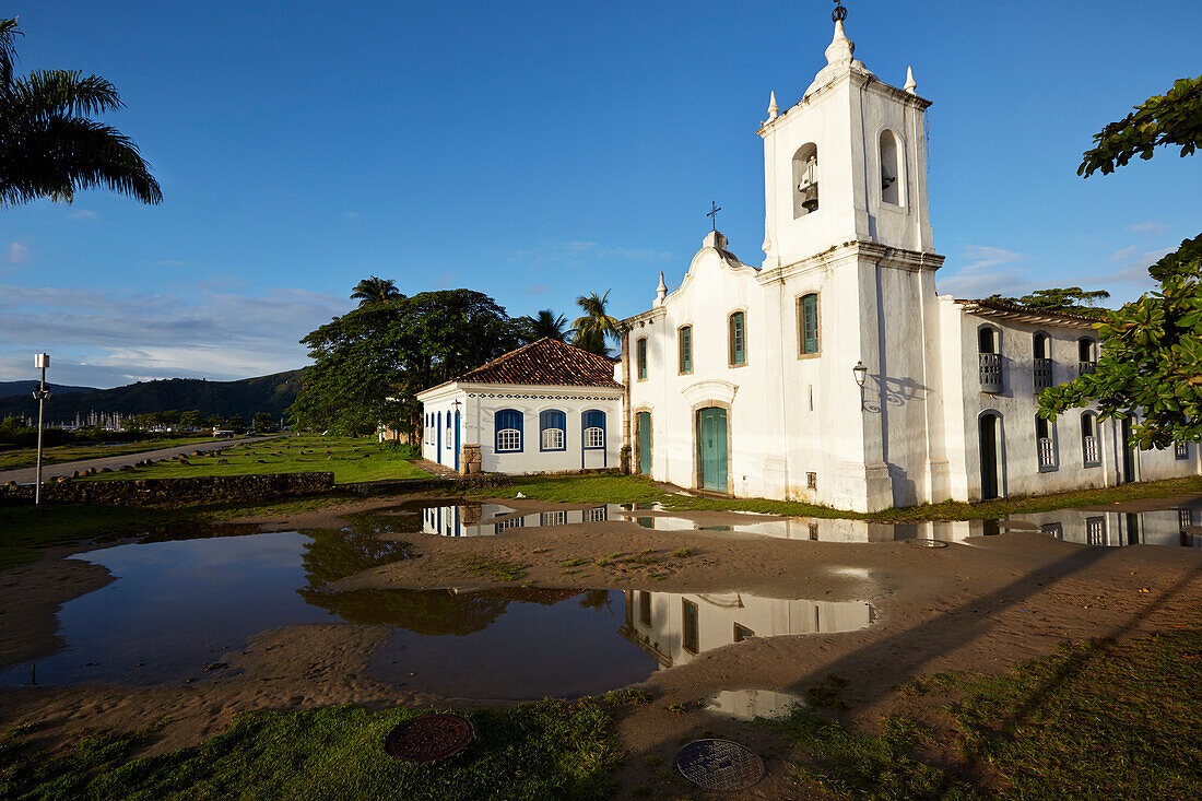 Morning sun, potholes, in the rain filled Rua Fresca, church Iglesia de Nostra Senora das Dores, historic old town, Paraty, Costa Verde, Rio de Janeiro, Brazil