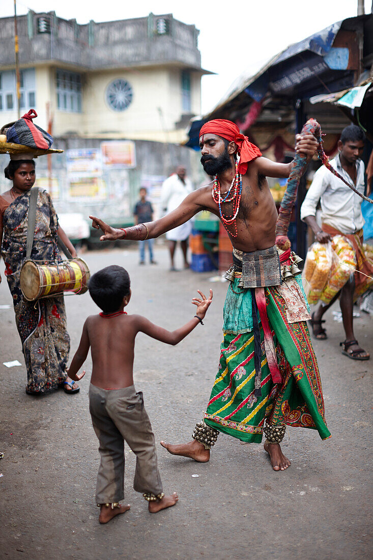' Nadoni - ''run from the place'', gypsies, juggler family between market stalls, mother drumming, son dancing and collecting money, father whipping and scourging himself, Hindus, in Valparai, Tamil Nadu, Western Ghats, India'