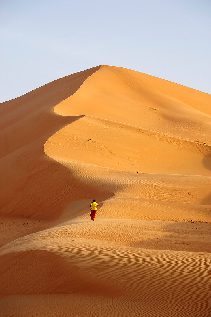 Sultanate of OMAN the Rub al Khali desert, a lonely man is walking towards a very high sand dune