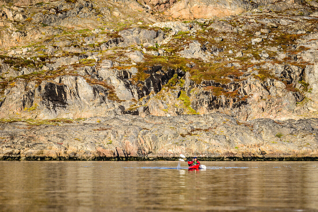 People paddling canoe near rock formations in remote river