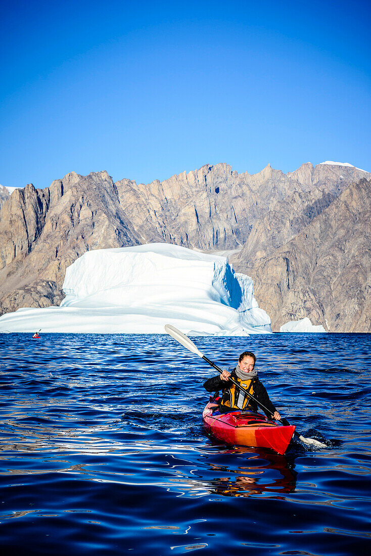 Woman paddling canoe near glaciers in remote river