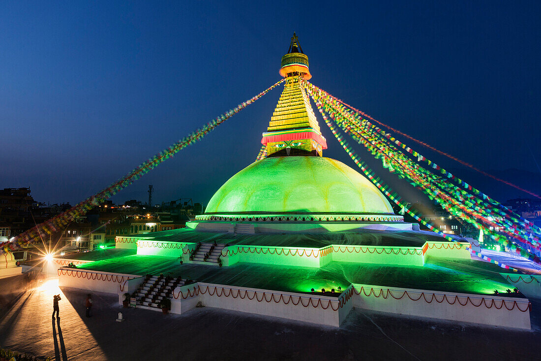 Prayer flags hanging from Boudhanath Stupa temple spire illuminated at night, Kathmandu, Kathmandu Valley, Nepal